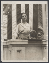 Photograph of Winifred Huck using the "carbon button" microphones on the rostrum in 1922.