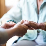 Caregiver holding an older woman's hands.