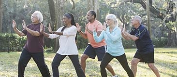 Group of older adults doing tai chi in the park