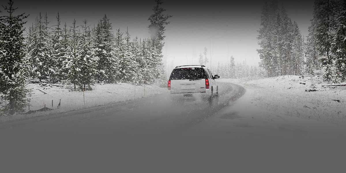 Photo of an SUV driving on a road during a snowstorm.