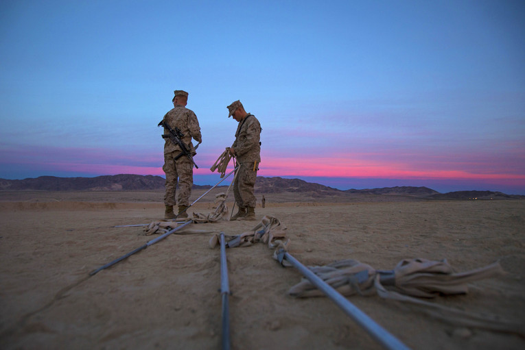 Two Marines prepare to set up obstacles.