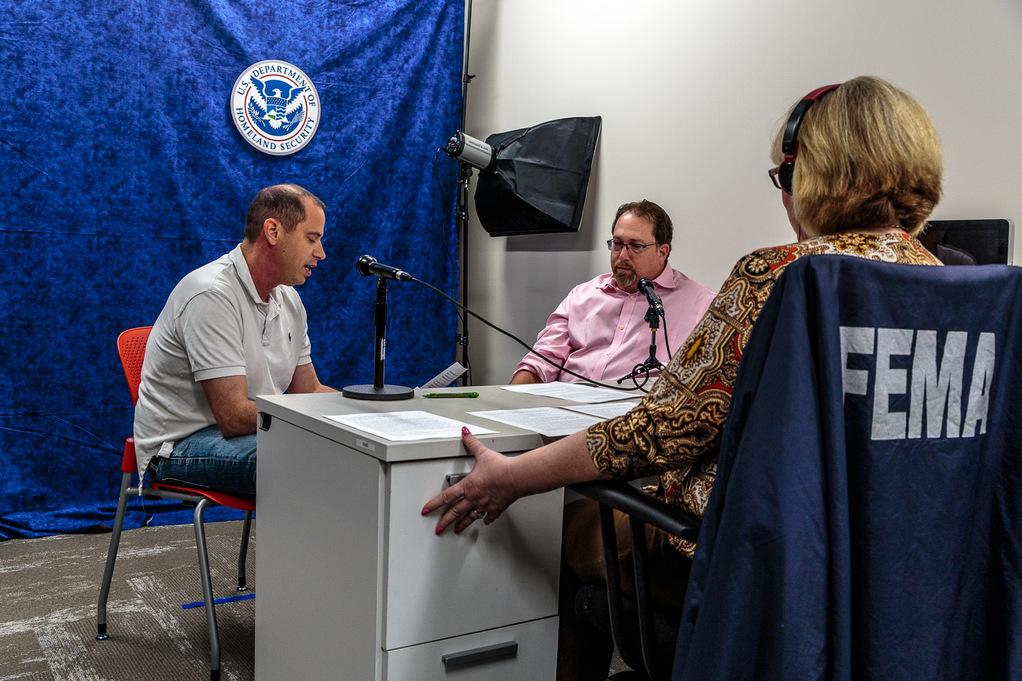 Three FEMA staff sit around a desk with microphones recording their conversation about financial preparedness for the FEMA podcast.