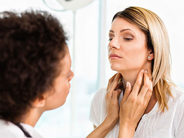 Young woman receiving thyroid exam from her doctor