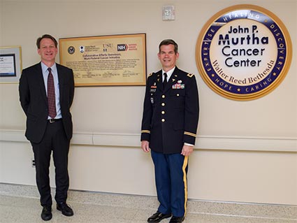 Dr. Norman Sharpless and Colonel Craog Shriver standing in front of a sign for the Murtha Cancer Center