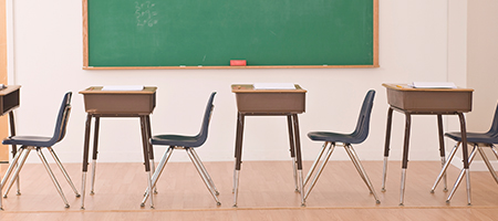 lessons that make cents banner - empty classroom with desks chairs and chalkboard