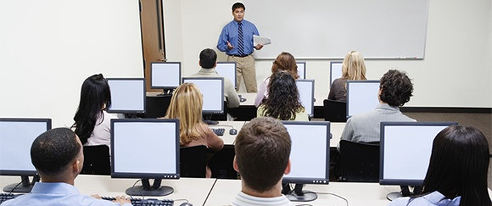 Teacher in front of a class looking at computer monitors