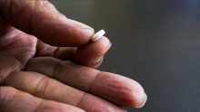 A photo of a hand holding a pill