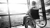 A photo of a man in a wheelchair looking out a large window