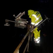 Bryce McClenny installs a rapid deployment gauge on a bridge at night