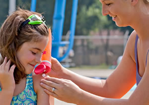 Photo of a lifeguard putting sunscreen on a girl.