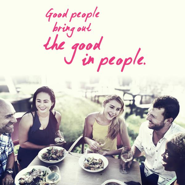 Four, 20-something friends, male and female, sitting around a table with text that says : "Good people bring out the good in people."