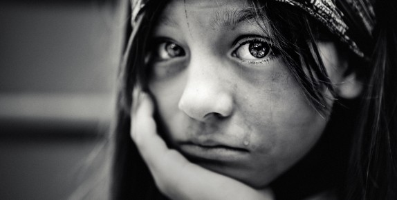 Girl with head resting in hand and a tear on her cheek