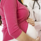 A pregnant woman stands next to a doctor filling out a form.
