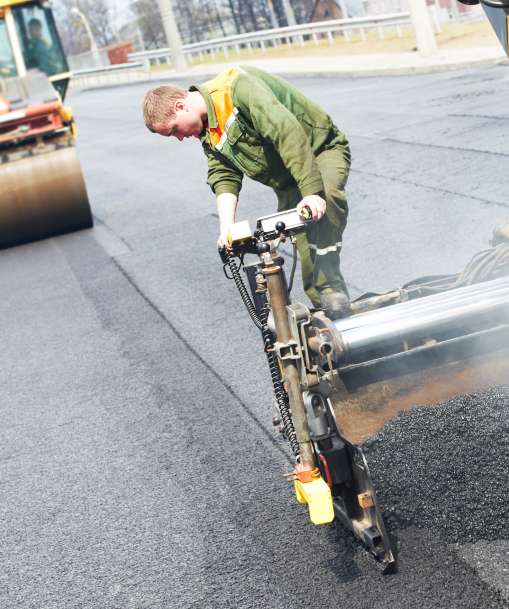 An asphalt paver lays hot asphalt along a stretch of road. 