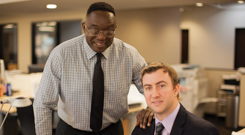 Picture of two men in an office smiling.