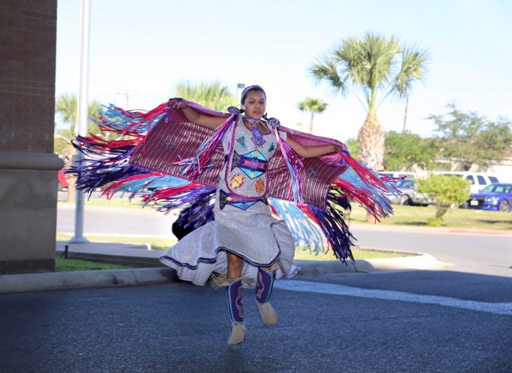 A young female member of the Lipan Apache Tribe of Texas dances while other tribe members play and sing in a drum circle during a special event held in observance of National Native American Heritage Month, which took place at the VA outpatient clinic in Harlingen, Texas, on November 16, 2018. (U.S. Department of Veterans Affairs photo by Luis H. Loza Gutierrez)