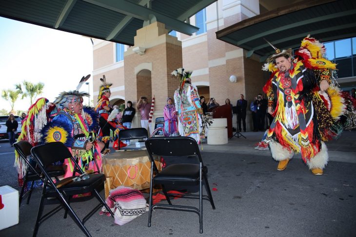 (At left) Robert Soto bangs a large drum and chants while male members of the Lipan Apache Tribe of Texas dance in front of a crowd of approximately 100 spectators during a special event held in observance of National Native American Heritage Month, which took place at the VA outpatient clinic in Harlingen, Texas, on November 16, 2018. (U.S. Department of Veterans Affairs photo by Luis H. Loza Gutierrez)
