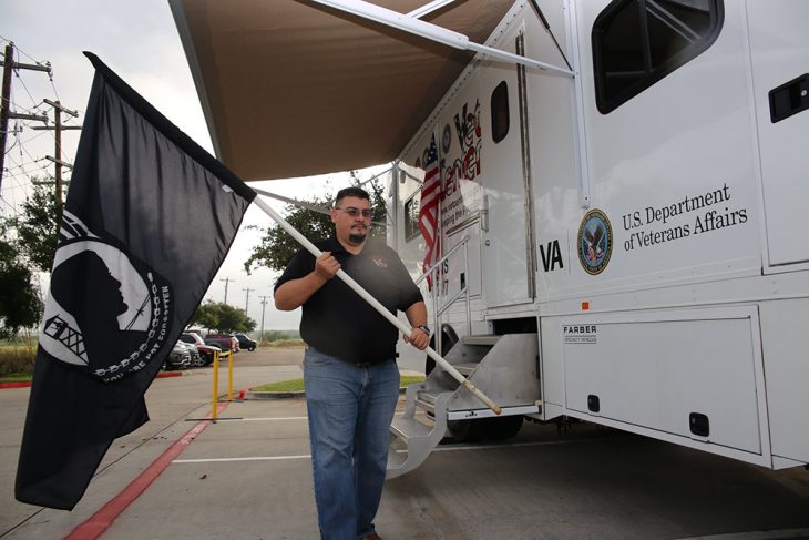 Jesus M. Perez Gloria a mobile unit specialist/driver brings out a POW*MIA flag that is used as part of the mobile Vet Center static display during the a drive thru and drop off event during the Boots & Badges care package drive held October 26, 2018, at Vet Center in Laredo, Texas. (U.S. Department of Veterans Affairs photo by Luis H. Loza Gutierrez)