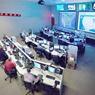 Picture of the NICC information sharing control room with rows of desks with computers and large TV screens on one wall.