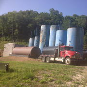 Tanker truck sits in from of several large tanks holding wastewater.