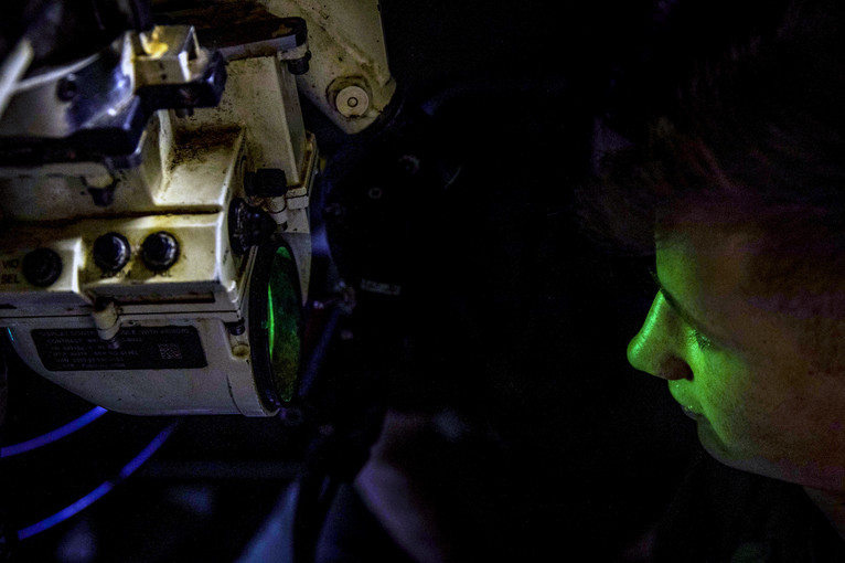 A sailor looks through a gun sight.