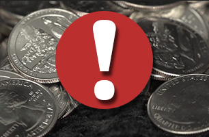 white exclamation point in a red circle in front of pile of quarters