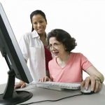 Older woman looking at clinical trials information online with her doctor