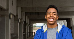 Smiling young man standing under a bridge