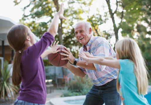 Older man playing basketball with two girls
