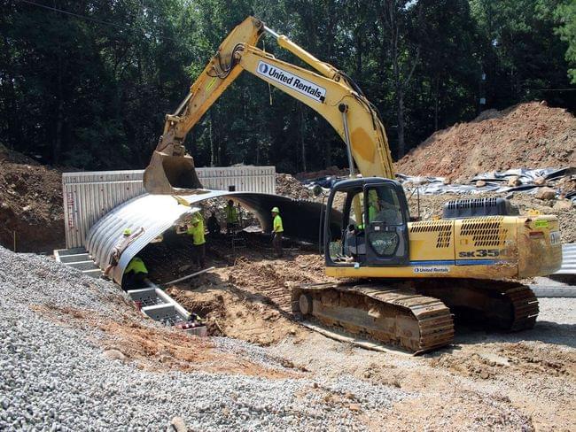 Heavy machinery moves a new culvert into place.