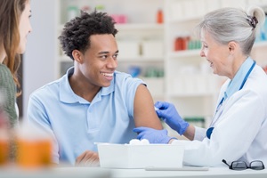 A nurse prepares to give a flu shot to a young man