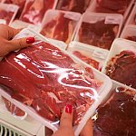 Woman holding packaged meat in the supermarket.