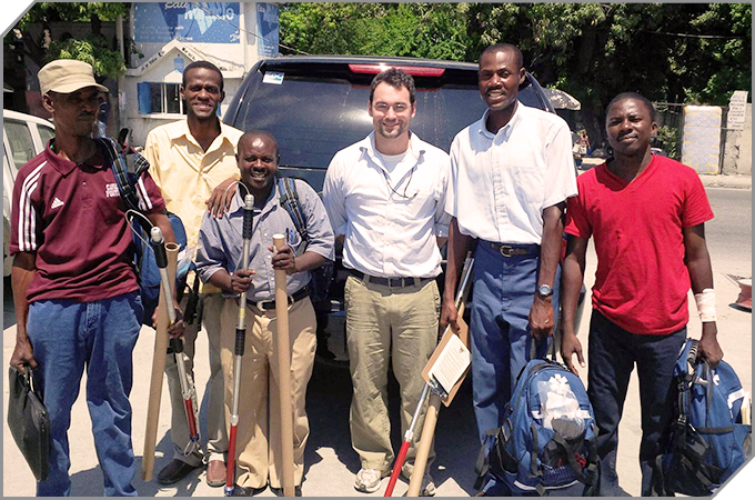 5 men from a rabies team in Haiti and a CDC vet stand with their gear looking at the camera