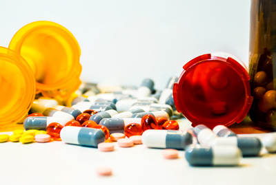 image of several prescription bottles and spilled pills on a white background