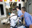 Two EMTs loading a patient into an ambulance.