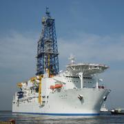 Image shows a large white ship with a drill rig