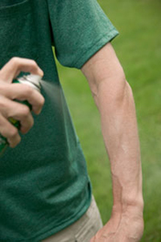 man spraying insect repellent on his arm