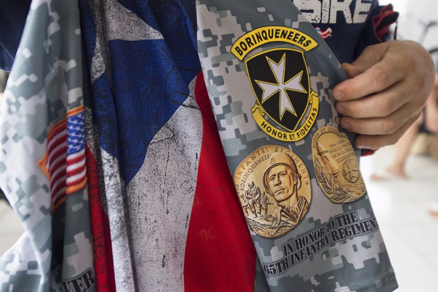A veteran holds a bicycle jersey with an imprinted emblem of Puerto Rico's 65th Infantry Regiment.
