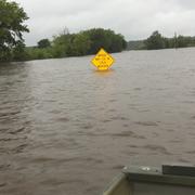 Image shows a partially submerged street sign from a flooded river