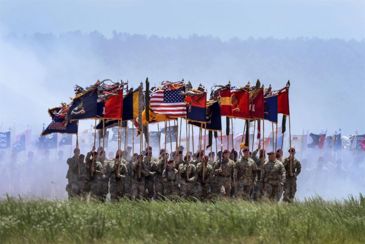 Soldiers carry flags as they march during a review.