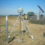 continuous GPS mounted on a tripod, located in a field, with a solar panel in the background