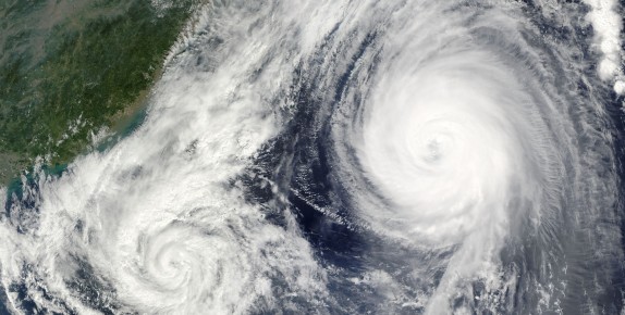 Photo showing satellite images of two swirling hurricanes at sea.