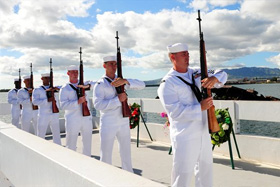 Photo of U.S. Navy sailors standing in a rifle salute.