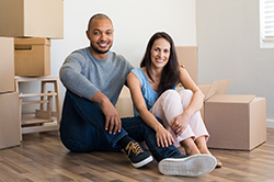 Foto de una pareja sentada en el piso con cajas para mudarse.