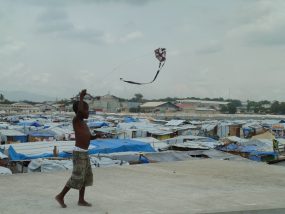 Child playing with kite in tent camp after earthquake, Port-au-Prince, Haiti, 2010.