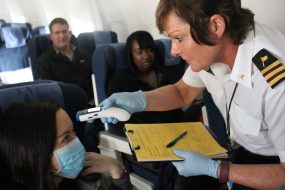 A CDC public health officer checks the temperature of a sick passenger onboard a flight that just landed in Chicago. Photo credit to Erin Rothney.