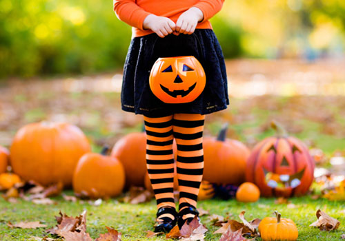 Girl in Orange and Black Tights Holding a Plastic Pumpkin