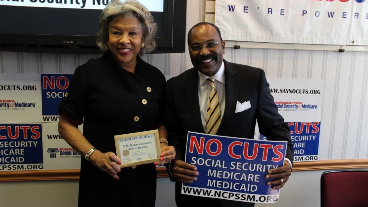 Congresswoman Beatty stands with "No Cuts to Social Security Medicare Medicaid" sign.