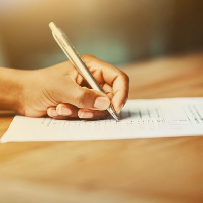 A hand filling out a document with a pen