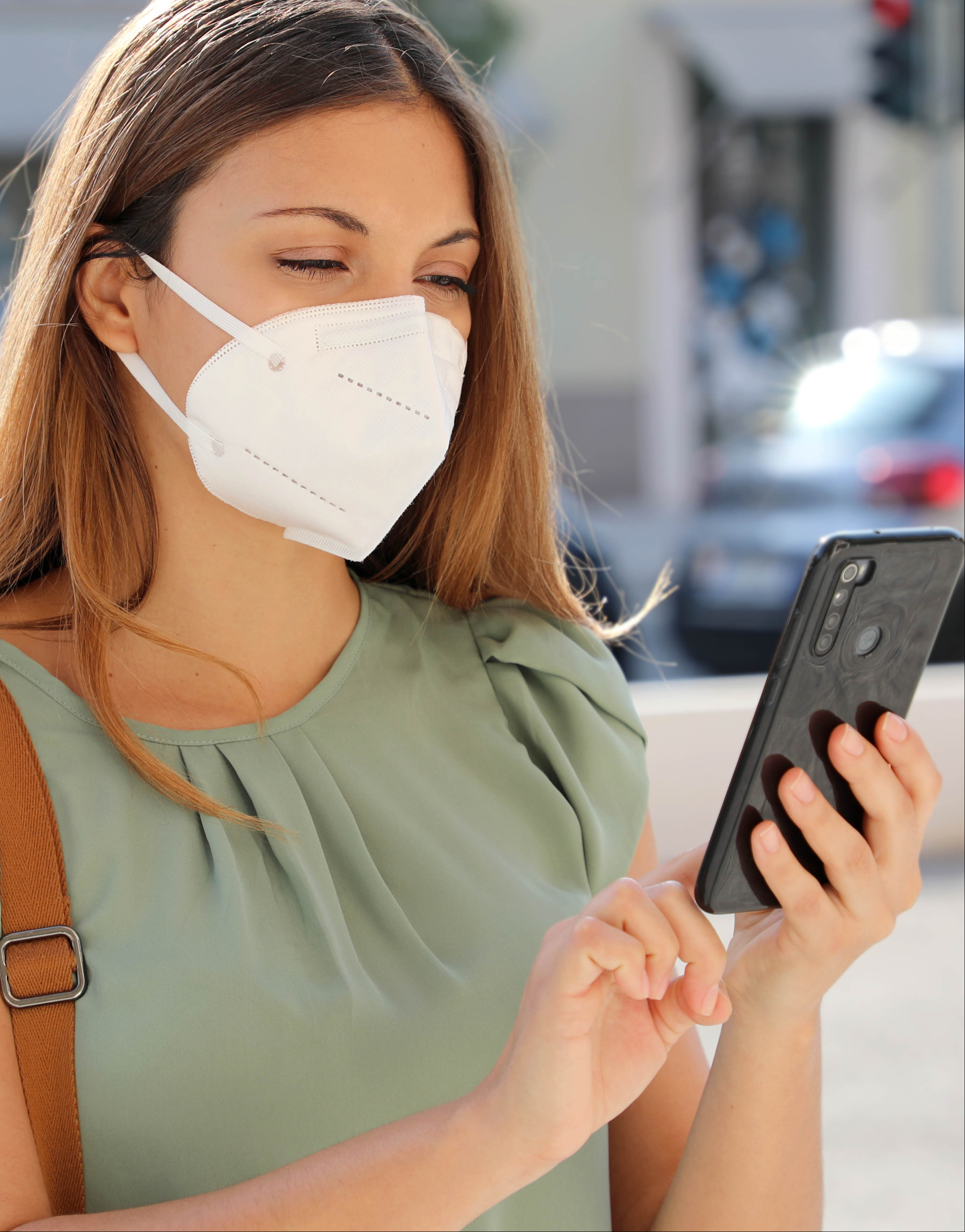 Image: woman wearing facemask using a mobile app